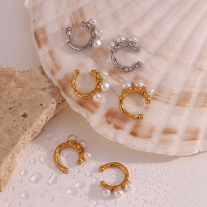 Detail showing gold and silver pearl ear clips on a shell with water droplets