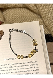 Close-up of citrine beaded bracelet with silver chain details on a vintage book