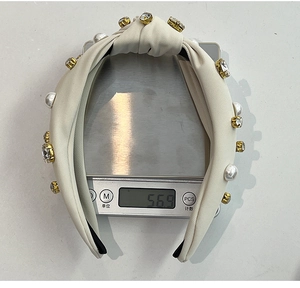 Detailed scale view of the beige knotted headband weighing 56.9g with pearls and crystals