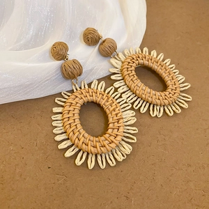 Gros plan de boucles d'oreilles bohèmes en raphia tressé avec texture naturelle