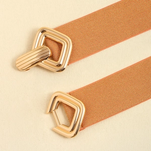 Détail de la boucle géométrique dorée sur une ceinture élastique métallique pour robe