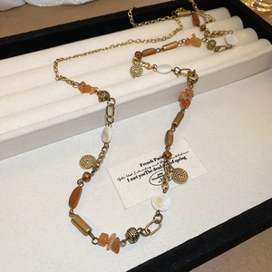 Dettaglio di una collana bohémien vintage con perline miste e ciondoli a moneta d'oro