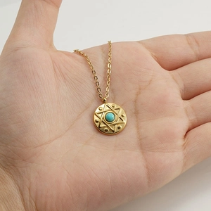 Gold star of David necklace with turquoise gemstone centerpiece displayed on palm