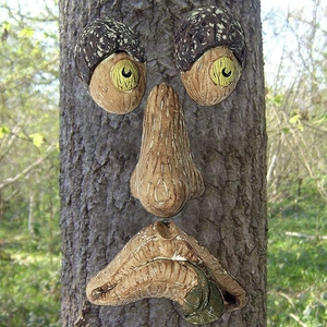 Detailed view of glow-in-the-dark resin bark face ornaments on a natural tree trunk