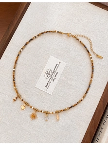 Detailed close-up of tiger eye beaded necklace with sun and star charms on vintage tray