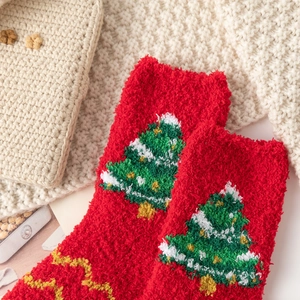 Détail de chaussettes de Noël en polaire corail rouge avec motif sapin et semelle dorée