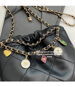Detail of black quilted bucket bag with colorful heart charms and chain strap