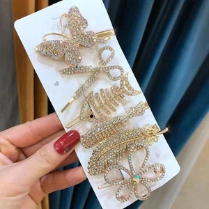 Close-up of 6 gold rhinestone hair clips including butterfly and scissors on white card