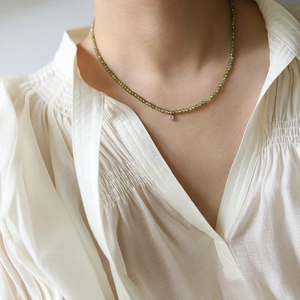 Close-up of olive green faceted beaded necklace with a sparkling round zircon pendant
