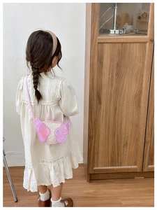 Pink sequined angel wing crossbody bag shown on a girl in a stylish outdoor setting