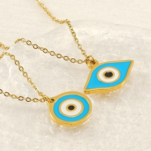 Gold stainless steel evil eye pendant necklace set with blue enamel accents on white cloth