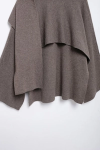 Detailed close-up showing texture of dark brown knit wrap shawl with irregular cape design