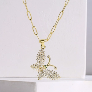 Close-up of 18K gold butterfly necklace pendant with pavé white and green zircons