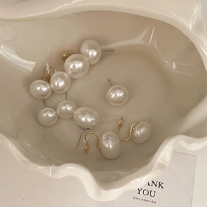 Lustrous pearl earrings in various sizes displayed elegantly in a shell-shaped ceramic tray