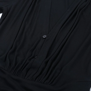 Close-up of deep V-neck black dress with pleated texture and matching button detail