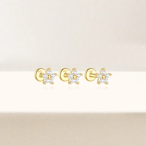 Three gold S925 sterling silver flower studs with white zircon inlay on beige backdrop