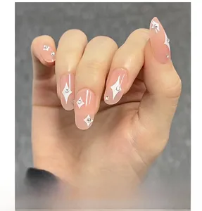Close-up of pink almond press-on nails with white stars and silver rhinestone details