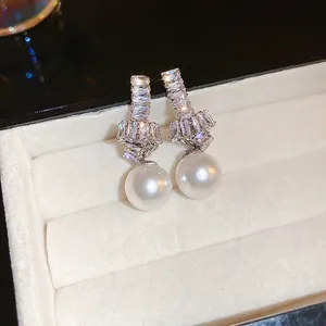 Elegant silver pearl earrings with knotted zircon crystals on a velvet jewelry box
