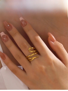 Close-up of a layered golden geometric wrap ring worn on a finger with a warm aesthetic
