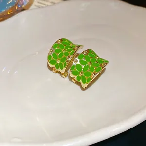 Minimalist C-shaped flower stud earrings with green enamel on a golden base