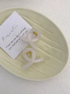 Detail of elegant cream and pink twist hair claws in a ceramic dish setup