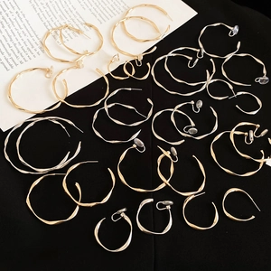 Macro view of twisted metal hoop earrings in gold and silver finish on black background