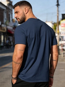 Rear view of a men's navy blue cotton T-shirt showcasing back tailoring and fit in sunlight