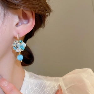 Detail of blue and white stone floral earrings with teardrop beads worn by a model