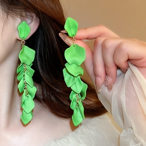 Close-up of elegant green floral petal tassel earrings worn by a model in soft lighting