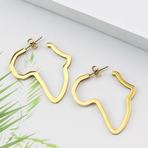 Détail de boucles d'oreilles dorées carte d'Afrique sur une feuille et fond blanc pur