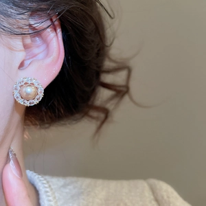Close-up of champagne pearl earrings with zircon flower petal setting on ear