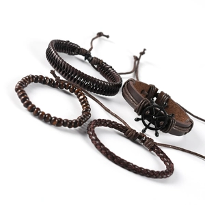 Close-up of four dark brown layered leather bracelets with wooden beads and a helm charm
