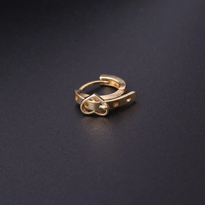 Detailed close-up of a golden heart-shaped ear cuff with zircon inlay on dark background