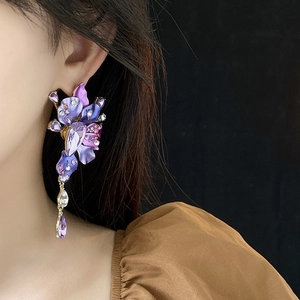 Detailed close-up of large purple floral drop earrings with rhinestones on a model