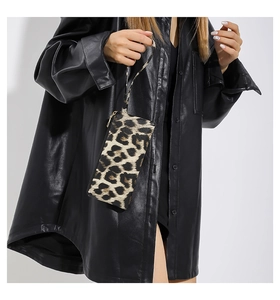 Close-up of leopard print wristlet bag with gold zipper and leather wrist strap