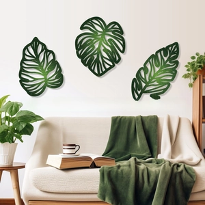Detailed view of three matte dark green monstera leaf wall art pieces on a white wall