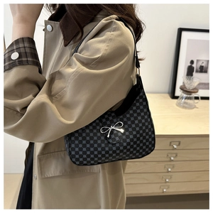 Detail of black crescent shoulder bag with silver bow accent and floral pattern