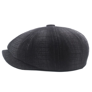 Detail view of dark grey newsboy cap with textured plaid pattern and top button