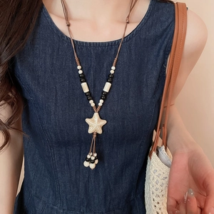 Detail view of a boho wax rope necklace with ceramic starfish pendant and beaded tassels