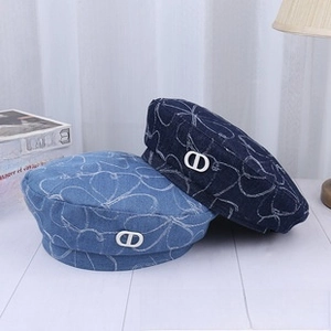 Close-up of denim beret hats with heart patterns and metallic CD logo detail