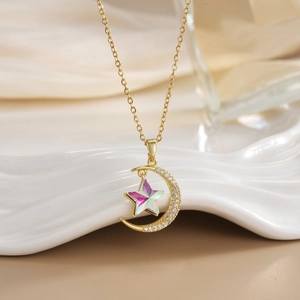 Macro shot of gold-plated moon and star pendant with zircons on a white ceramic plate