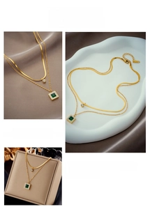 Detail of double-layer gold chain necklace with green square emerald pendant and small zircon