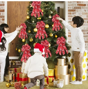 Children decorating Christmas tree with red linen bows and festive gift boxes in a warm room
