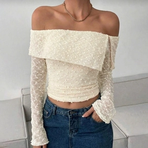 Detail of off-white off-shoulder top featuring textured 3D polka dot lace fabric