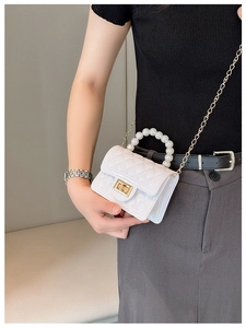 Close-up of white mini jelly bag with pearl handle and golden chain on a model