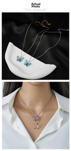 Detail of a gradient butterfly necklace on black satin background and on model