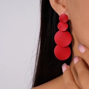 Close-up of red matte geometric round earrings worn by a model in a fashion shot