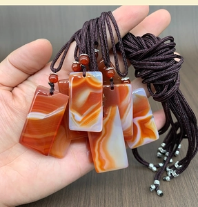 Close-up of rectangular agate pendants with natural patterns and woven neck cord
