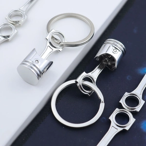Detailed macro view of silver metal car piston and connecting rod keychain accessories
