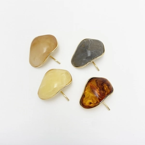 Detail of four irregular resin hair clips with marble and amber patterns and gold metal edges